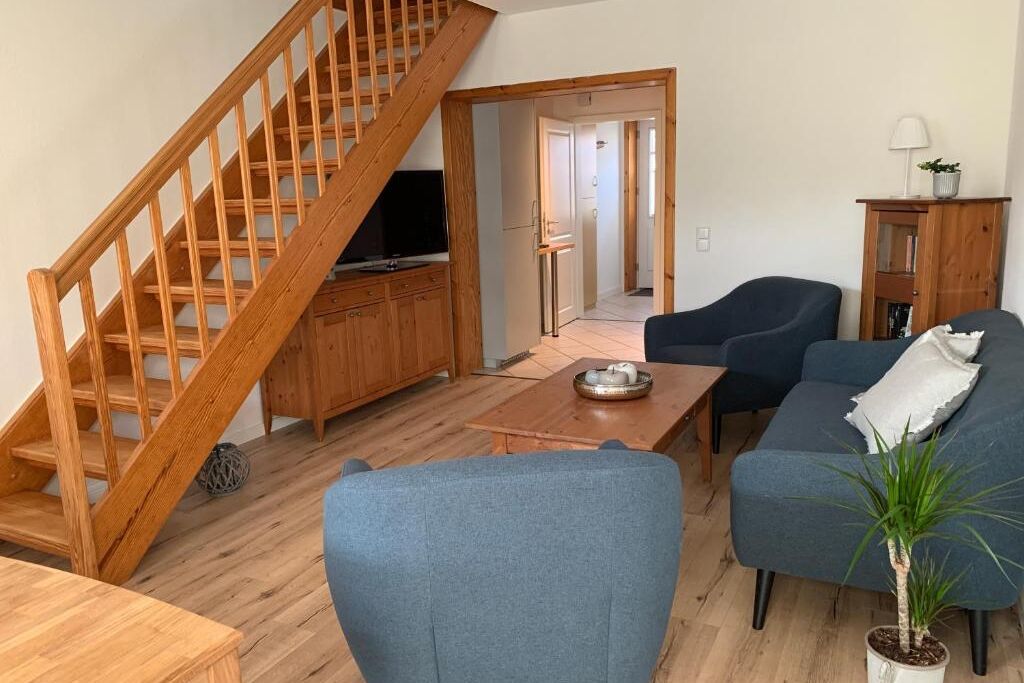 Wohnzimmer mit blauen Polstermöbeln und Holztreppe