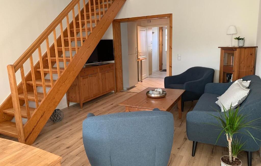 Wohnbereich der Lüttje Koje mit Sofa, Sesseln und Holztreppe