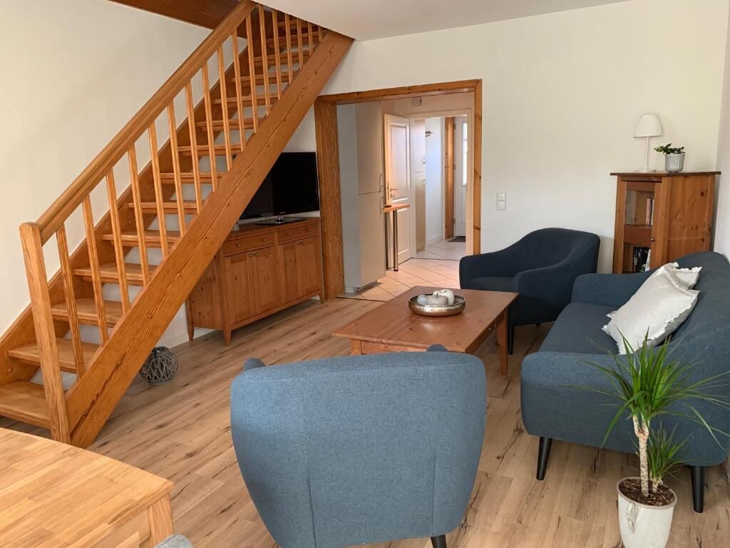 Wohnzimmer mit blauen Polstermöbeln und Holztreppe